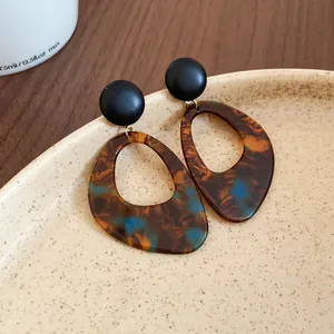 Close-up of vintage tortoise shell earrings with a textured black stud finish.