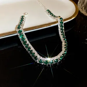 Macro detail of emerald green gemstone necklace with crystal halo in silver finish
