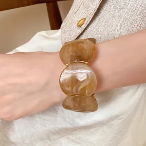 Elegant amber marbled acrylic bracelet with a smooth rounded stone-like design.