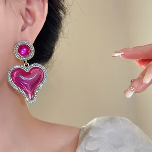 Détail de boucles d'oreilles cœur vintage en résine rose avec bordure strass