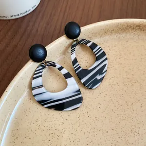 Close-up of retro black and white marbled striped teardrop hoop earrings on a plate.