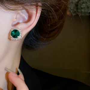 Detailed macro view of an elegant emerald green gemstone earring with a sparkling diamond halo