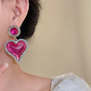 Vue détaillée de boucles d'oreilles cœur en résine vintage avec strass brillants.