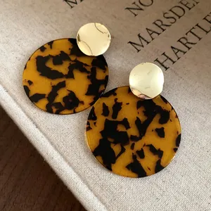 Detailed macro shot of vintage tortoiseshell leopard print round stud earrings with gold accents