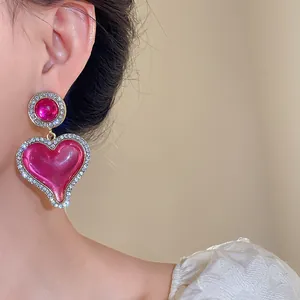 Vue détaillée de boucles d'oreilles vintage en résine rose avec bordure en strass.