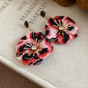 Detailed macro view of retro leopard print flower earrings with a sparkling crystal center