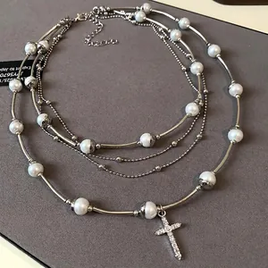 Elegant multi-layered pearl necklace with crystal cross pendant for a vintage aesthetic look