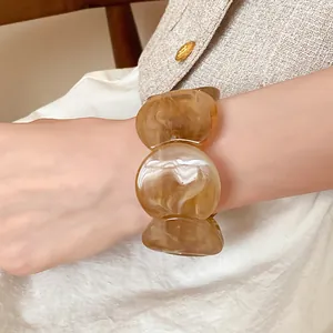 Detailed close-up view of an elegant amber marbled acrylic chunky bracelet on a model's wrist