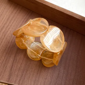 Close-up of amber marbled acrylic chunky linked bracelet on a wooden background