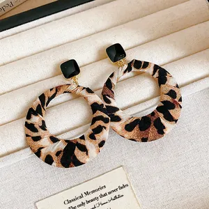 Close-up of vintage leopard print fabric wrapped hoop earrings on a beige tray.