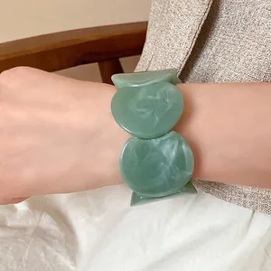 Close-up detail of a green marbled acrylic bracelet showing elegant swirl patterns