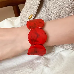Macro view of a vibrant red marbled acrylic bracelet with oversized circular spliced segments