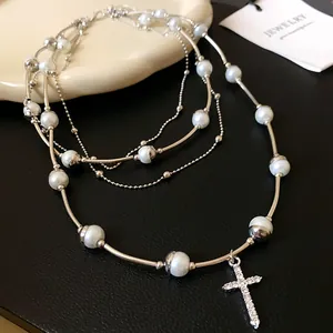 Detailed view of silver-toned multi-layered necklace with pearls and cross pendant