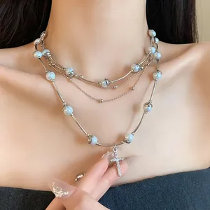 Detail view of multi-layer silver necklace with pearls and crystal cross pendant
