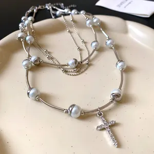 Close-up of multi-layered pearl necklace with rhinestone-encrusted cross pendant