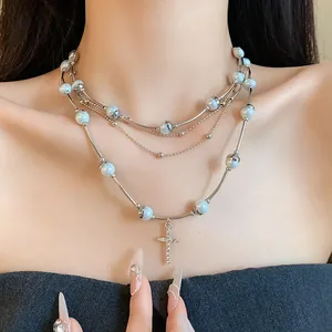 Detailed view of multi-layered pearl necklace with a rhinestone cross pendant