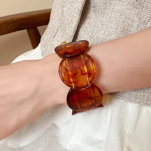 Detailed close-up of amber acrylic marbled round bracelet on model's wrist