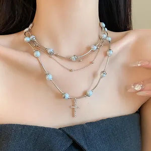 Close-up of a stylish multi-layered blue pearl necklace with a rhinestone cross charm