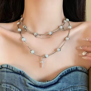 Detailed view of a layered silver necklace featuring pearls and a sparkling cross pendant