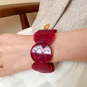 Close-up detail of a deep red acrylic marble chunky bracelet worn on a model wrist