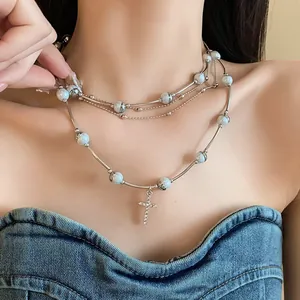 Close-up of layered silver necklace with pearls and crystal cross pendant on model