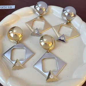 Close-up of geometric metallic drop earrings with rhinestones on a decorative plate