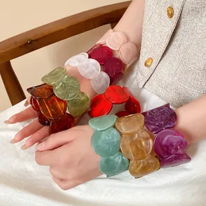 Detailed view of multi-colored acrylic bracelets with elegant marble texture on wrist