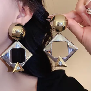Detailed view of oversized geometric rhombus earrings with rhinestone accents.