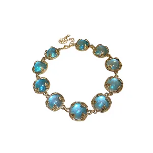 Vintage gold-tone geometric necklace with glowing blue resin stones on white background