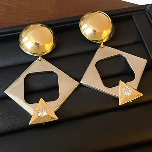 Close-up of geometric gold and silver earrings with small rhinestones on black tray