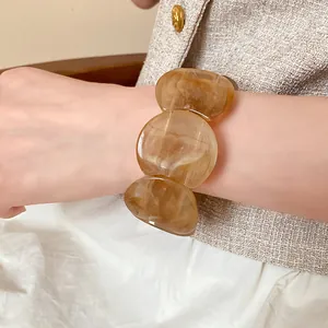 Detailed view of an amber marbled acrylic bracelet with round chunky links on a wrist