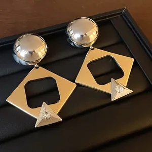 Detailed view of geometric earrings with gold square hoops and silver rhinestone accents.