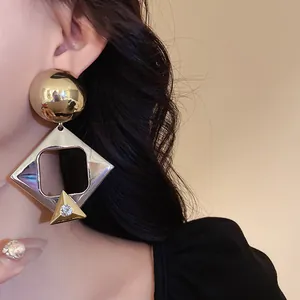 Close-up of exaggerated geometric diamond-encrusted silver needle earrings on ear.