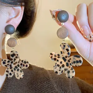 Close-up detail of leopard print flower earrings with wooden accents in retro Maillard style.