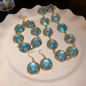 Detail view of a vintage court style resin jewelry set with blue stones and gold-tone finish