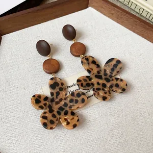 Detailed shot of leopard print flower earrings with wooden accents in vintage Maillard style