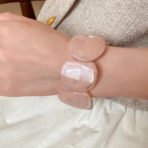 Close-up detail of a pink acrylic marbled round-link bracelet worn on a woman's wrist.