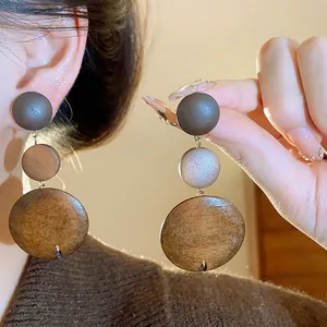 Detailed close-up of vintage Maillard style wooden triple-disc dangle earrings