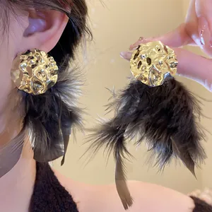 Macro view of gold hammered stud earrings with elegant black feather tassels for women