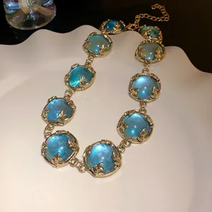Close-up of vintage gold necklace with round blue resin stones on a white plate