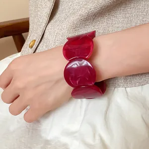 Detailed view of dark red acrylic round link bracelet with marbled ink wash texture on wrist