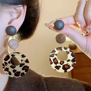 Close-up detail of retro leopard print drop earrings featuring layered wooden studs.