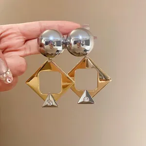 Detailed view of oversized geometric rhombus earrings with silver sphere and rhinestone