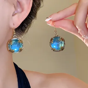 Close-up detail of vintage blue resin orb earrings with golden leaf frame design