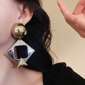 Detailed close-up view of oversized geometric earrings with rhinestones on an Asian model.