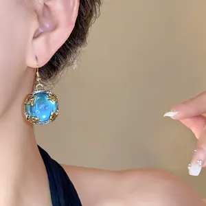 Close-up detail of a vintage court style resin earring featuring a bright blue stone