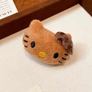 Detail showing the soft brown plush texture of a cat-shaped brooch with embroidered face.
