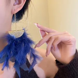 Close-up detail of blue feather tassel earrings with gold hammered metal accents.