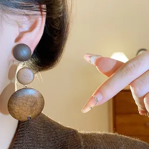 Close-up of retro Maillard style layered wooden drop earrings on model's ear