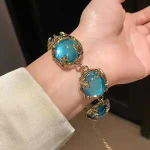 Detail view of vintage gold bracelet with large blue resin stones on wrist